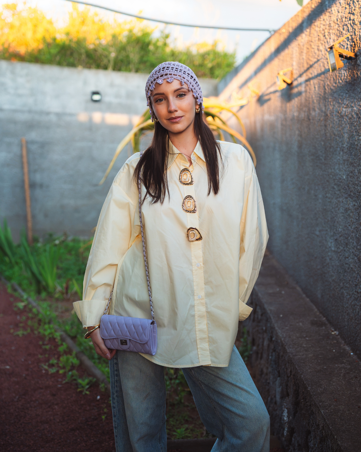 Femme portant un chemisier oversize jaune pastel à gros boutons dorés avec un jean large