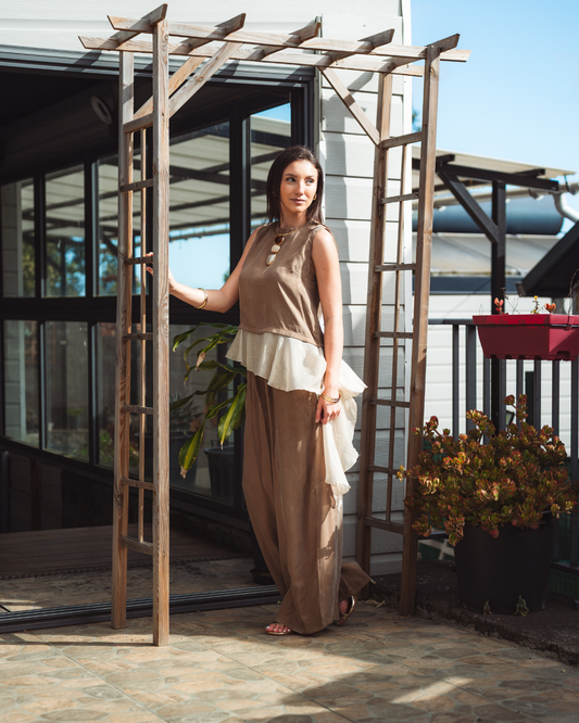 Femme portant un ensemble camel composé d’un top sans manches à volant en voile crème et d’un pantalon large fluide