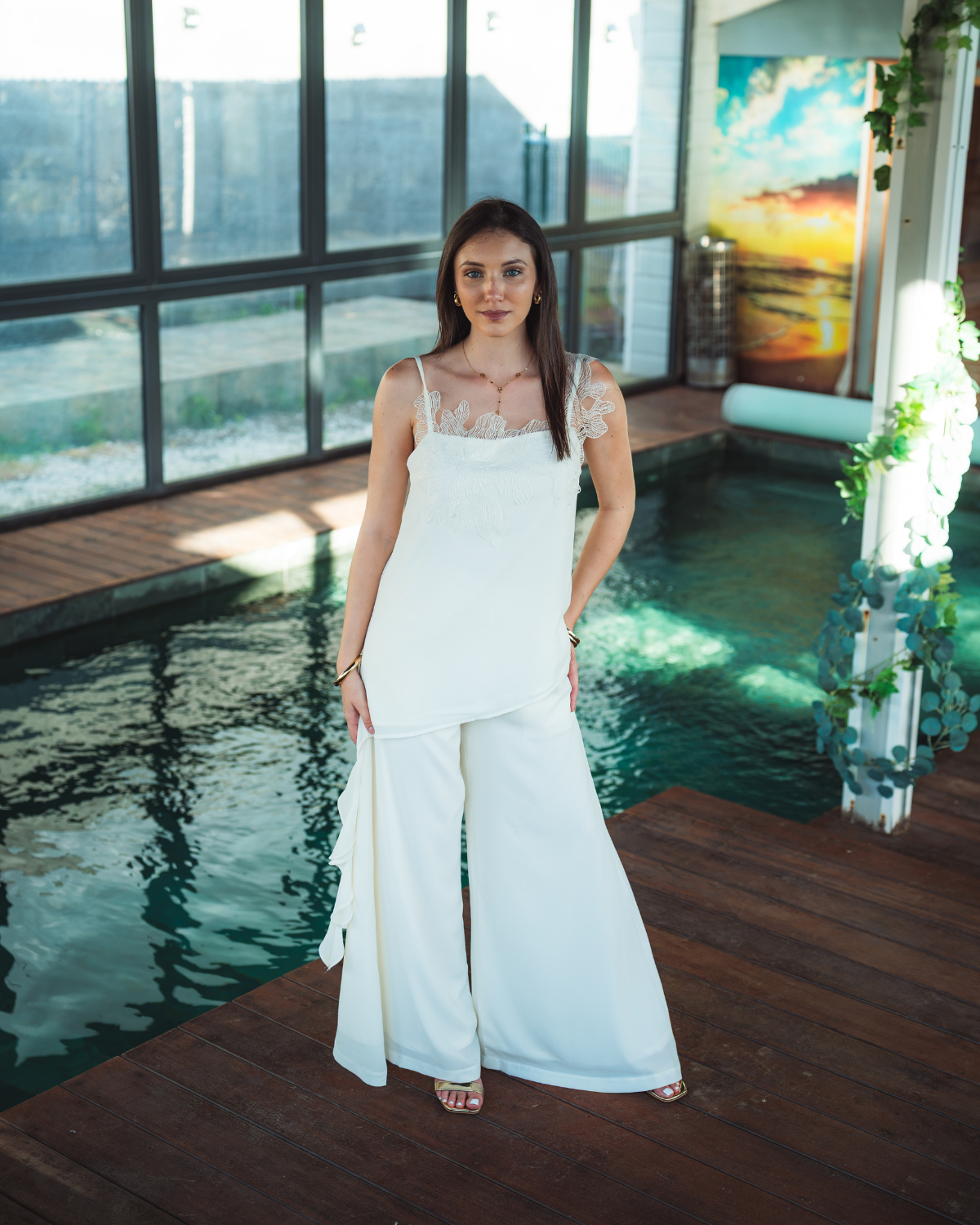 Femme portant un ensemble blanc cassé composé d’un top en dentelle asymétrique et d’un pantalon large fluide